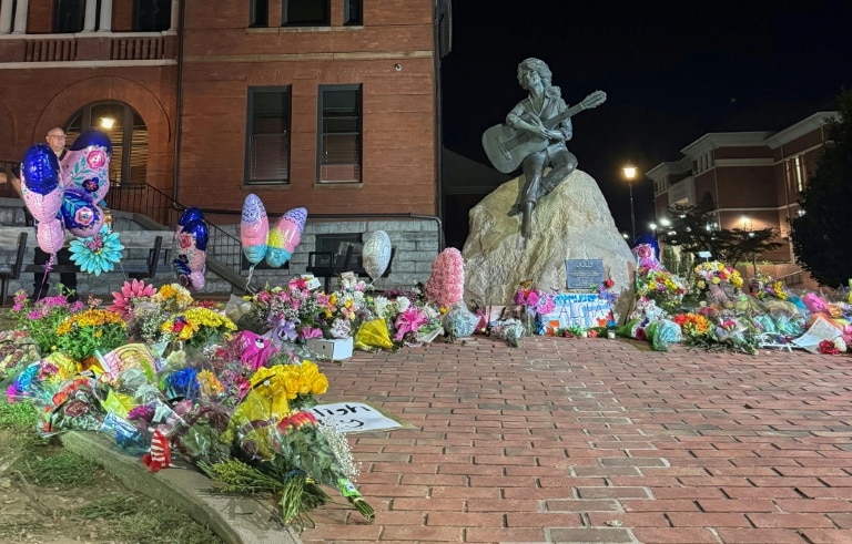 <p>Au pied de la statue de Dolly Parton, des fleurs déposées en hommage le 25 août 2026 à Sevierville (Etats-Unis)</p>