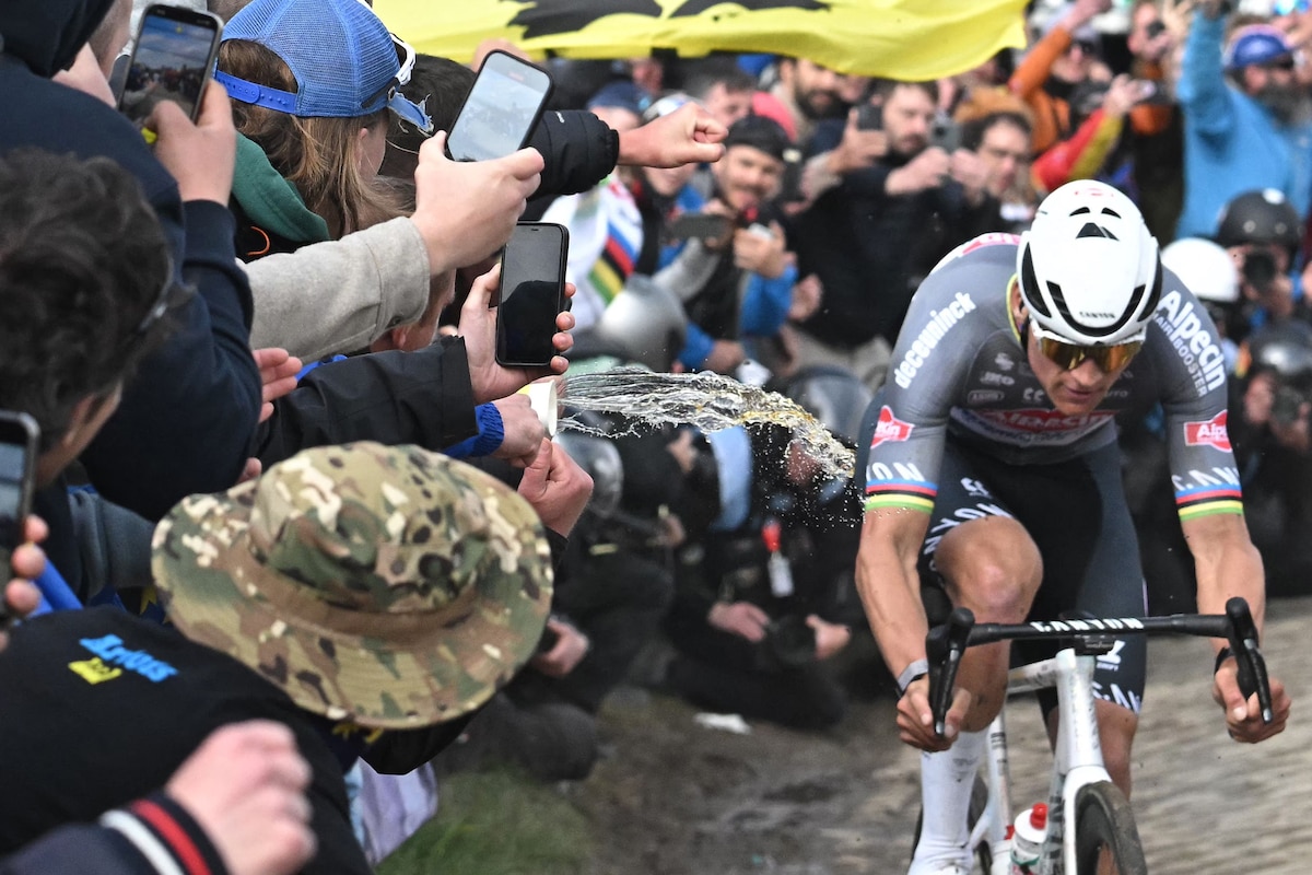 A spectator spills liquid as Alpecin-Deceuninck's Dutch rider Mathieu van der Poel cycles during the 122nd edition of the Paris-Roubaix one-day classic cycling race, 259,2 km between Compiegne and Roubaix, northern France on April 13, 2025. (Photo by Bernard PAPON / POOL / AFP)