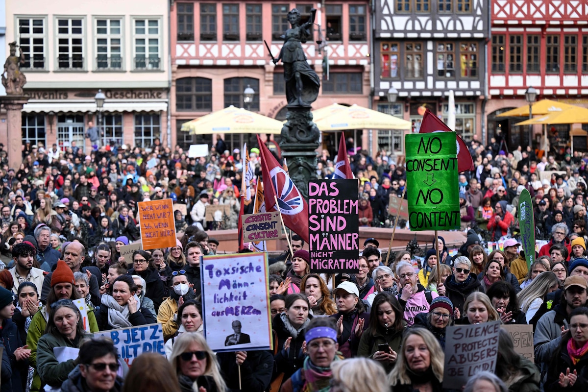 Participants demonstrate with a placard with the lettering reading 'Men are the problem, not migration' against digital violence at Frankfurt's central Roemer Square, western Germany on March 30, 2026. The initiative "Es reicht!" (It's Enough!) had called for the demonstration, which is also held in support of German TV presenter and actress Collien Fernandes. The allegations from Fernandes, 44, against her ex-husband, actor Christian Ulmen, have sparked intense media debate about the "digital violence" increasingly perpetrated on the internet, mostly against women. German prosecutors said on March 27, they have revived a probe into her ex-husband after claims that he spread AI-generated pornographic images of her on the internet. The government has responded to the outcry by pledging to introduce laws to punish the creation and distribution of sexualised deepfakes. (Photo by Kirill KUDRYAVTSEV / AFP)